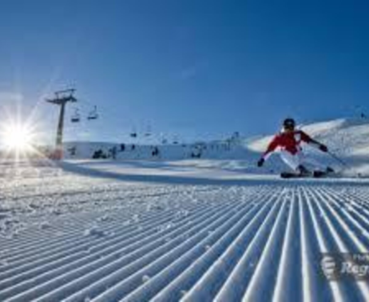 Präparierte Skipiste mit Skifahrer, Skilift und Sonnenschein, eine Winteraktivität in der Nähe des Bauernhofs.