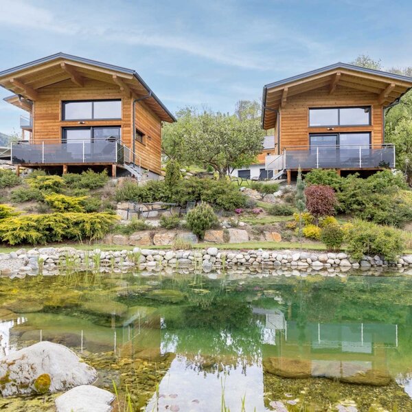 Hofchalets des Bauernhofs mit Terrassen und einem Teich im Vordergrund.