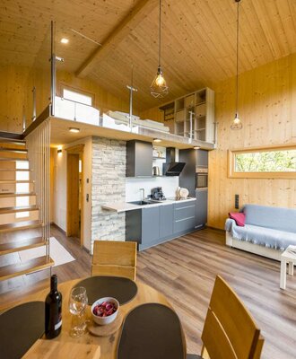 Offener Wohnbereich im Chalet mit moderner Küche, Esstisch, Sofa und Galerie mit Schlafbereich. copyright: ELISABETH FRÖHLICH photography