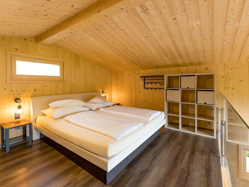 Schlafzimmer im Chalet mit Boxspringbett oder Wasserbett Holzvertäfelung und Ablageregal.