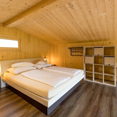 Schlafzimmer im Chalet mit Boxspringbett oder Wasserbett Holzvertäfelung und Ablageregal.