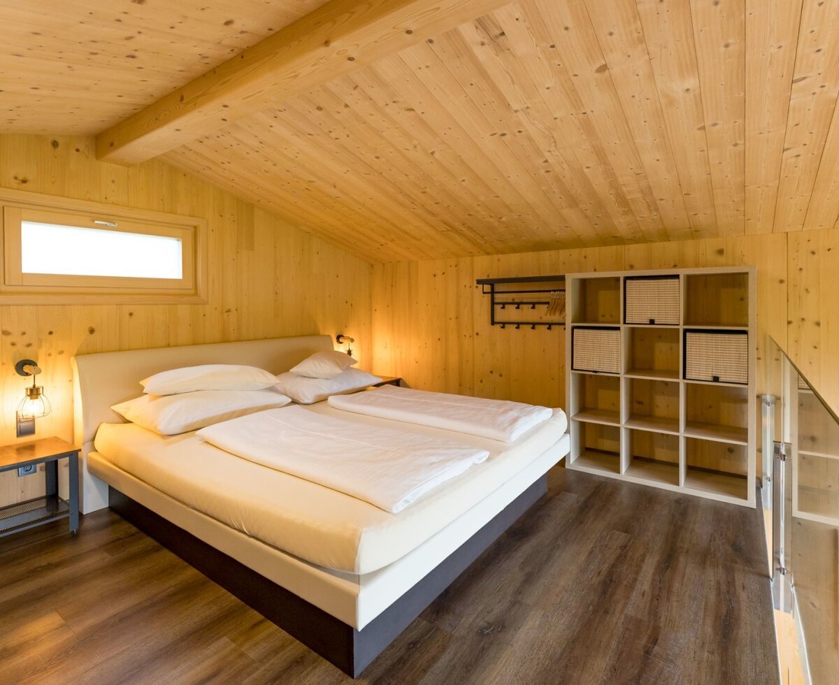 Schlafzimmer im Chalet mit Boxspringbett oder Wasserbett Holzvertäfelung und Ablageregal.