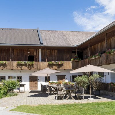 Der einladende Innenhof des Bauernhofs mit gemütlichen Sitzbereichen unter schattigen Sonnenschirmen.