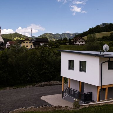 Außenansicht des modernen Apartments auf dem Bauernhof mit Blick auf das Dorf und die bergige Umgebung.