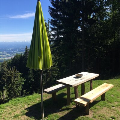 Der Außenbereich des Hofes bietet einen Holztisch mit Bänken, Sonnenschirm und weitreichendem Ausblick.