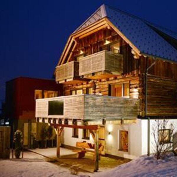 Aussenansicht des Bauernhofs bei Nacht im Winter, mit beleuchtung und Balkonen.