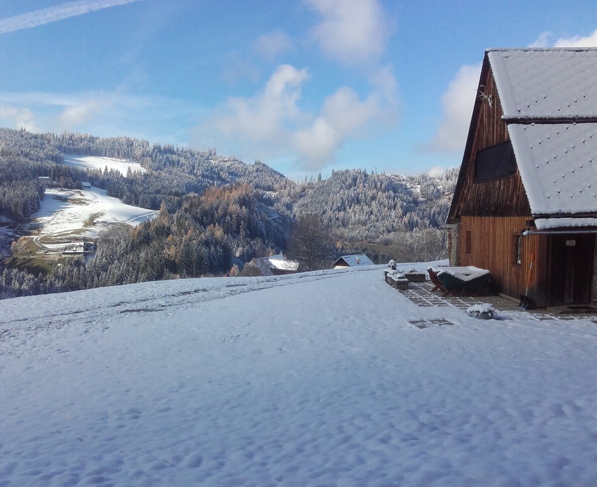 Das Gebäude des Hofs mit schneebedeckter Terrasse und Aussicht auf die winterliche Berglandschaft.