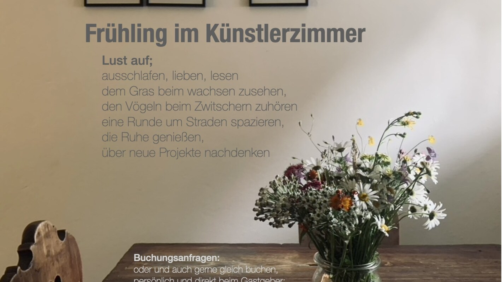 Holztisch mit einem Strauß Wildblumen und gerahmten Zeichnungen an der Wand im Bauernhof.