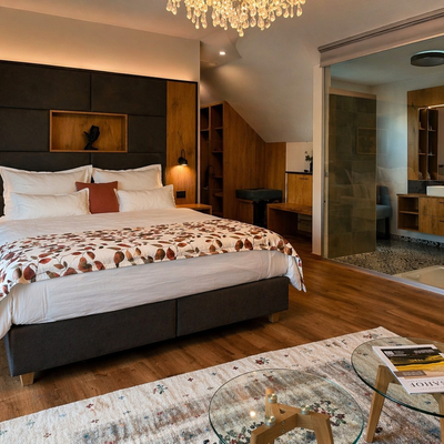 Ein geräumiges Doppelzimmer am Bauernhof mit einem einladenden Doppelbett, warmen Holzelementen und einem eleganten, offenen Badezimmerbereich.