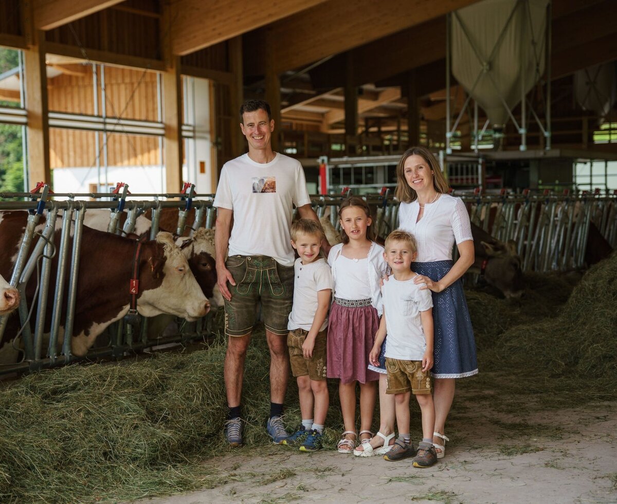 Die Familie des Bauernhofs Linharterhof mit Kühen im Stall.
