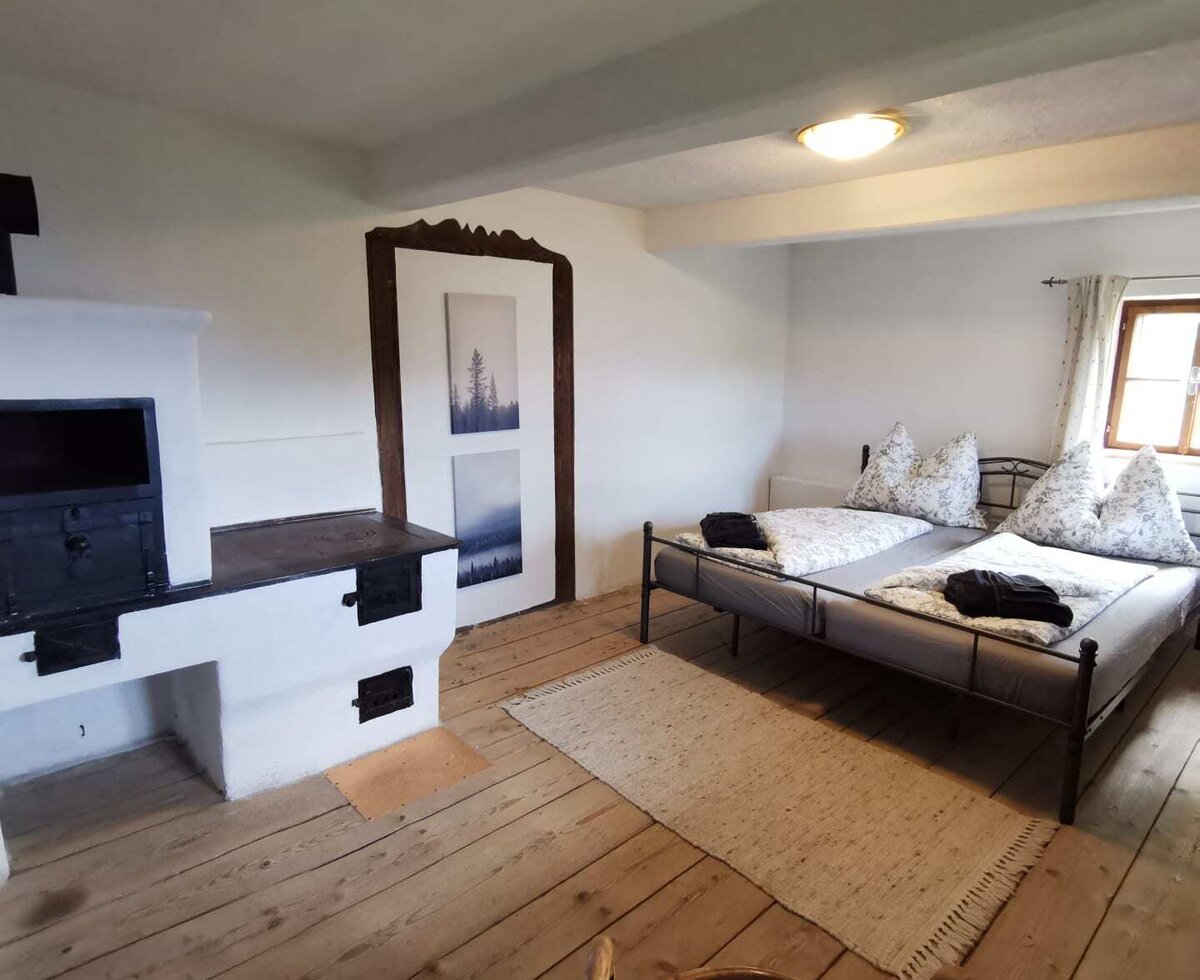 Schlafzimmer mit Doppelbett, traditionellem Tischherd und originalen Holzdielenboden.