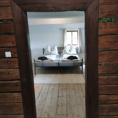 Blick ins Schlafzimmer mit Doppelbett und Holzdielenboden