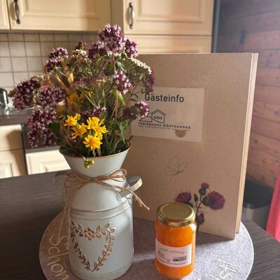 Ein herzlicher Empfang auf der Alm mit einem liebevoll arrangierten Wildblumenstrauß, einer Gästeinformation und einem süßen Willkommensgruß.