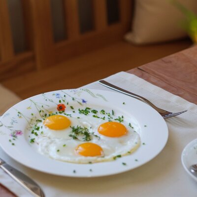 Teller mit Spiegeleiern und frischen Kräutern zum Frühstück auf dem Bauernhof.
