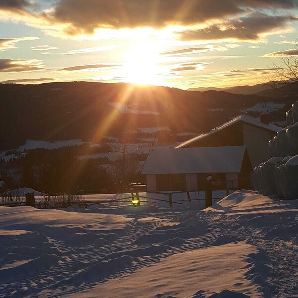 Aussicht auf die verschneite Berglandschaft vom Bauernhof bei Sonnenuntergang.