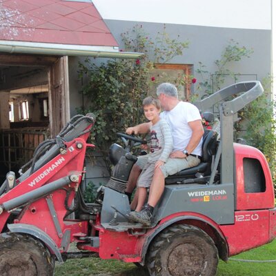 Ein Kind und ein Erwachsener auf einem Hoflader des Bauernhofs.