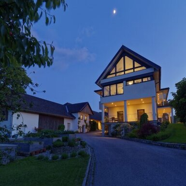 Die beleuchtete Außenansicht des Bauernhofs bei Einbruch der Dunkelheit.