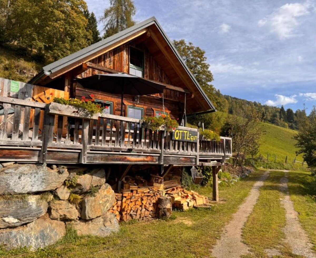 Die Ottls Hütte aus Holz mit einer einladenden Terrasse inmitten idyllischer Natur.