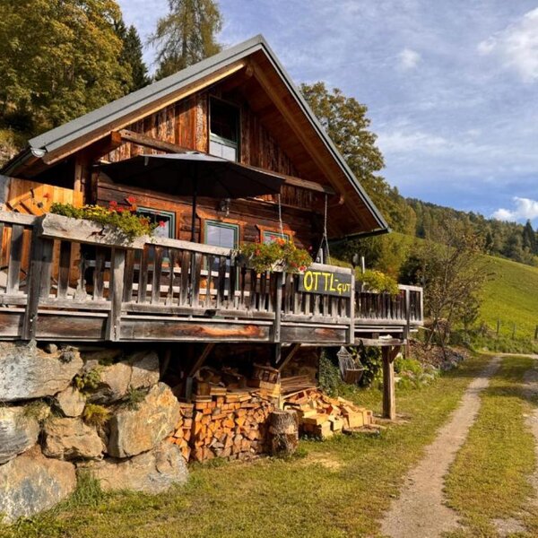 Die Ottls Hütte aus Holz mit einer einladenden Terrasse inmitten idyllischer Natur.
