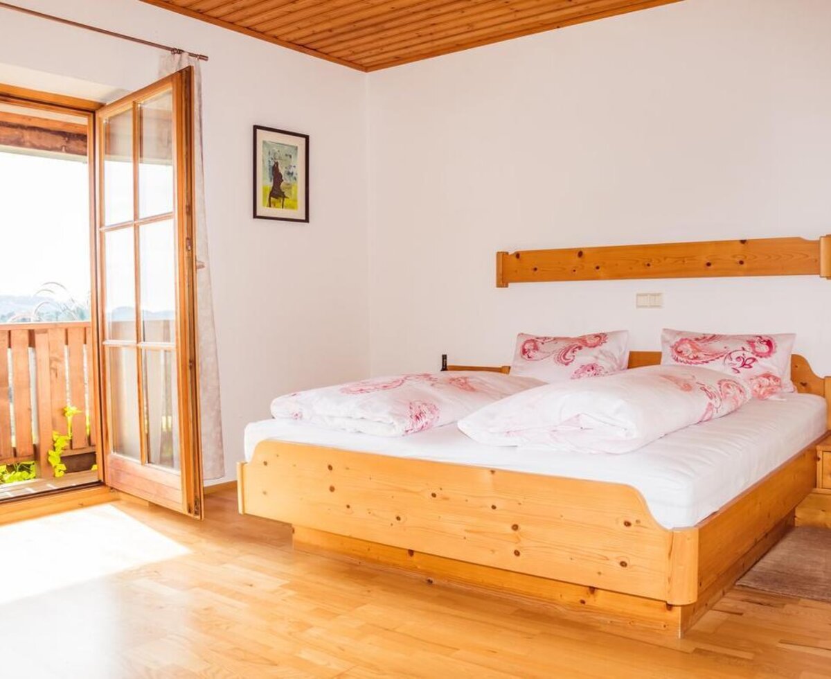 Doppelzimmer mit Holzbett, Holzboden und Zugang zum Balkon. (c) Gregor Schiefer