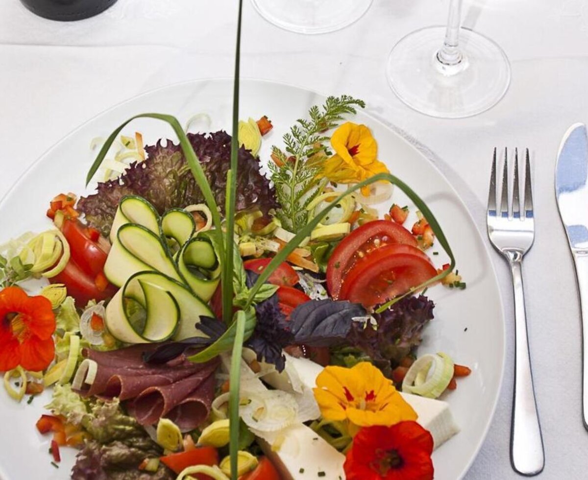 Teller mit frischem Salat, Zucchini, Tomaten, Aufschnitt, Käse und essbaren Blüten. (c) Gregor Schiefer