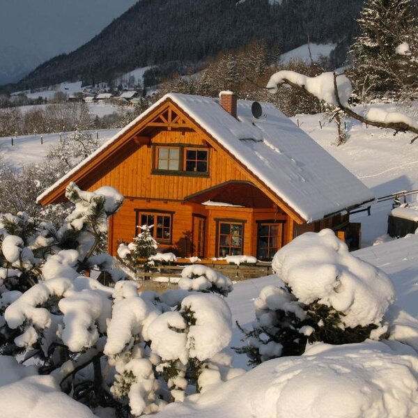 Das Ferienhaus im Winter, umgeben von Schnee und Bergen.