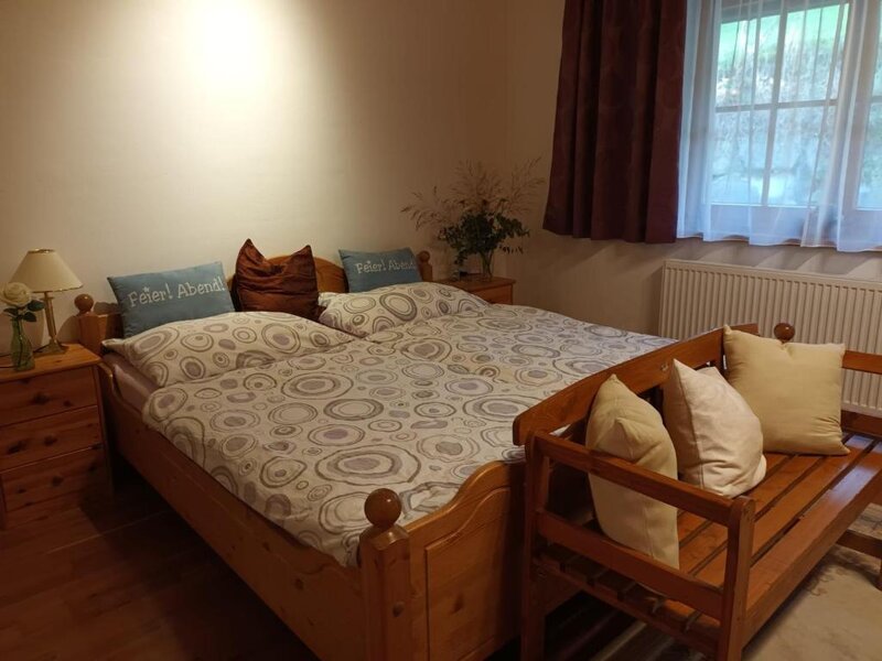 Schlafzimmer im Bed and Breakfast mit Doppelbett, zwei Nachttischen, einer Holzbank und einem Fenster mit Vorhängen.