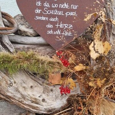 Ein herzförmiges Schild mit der Aufschrift 'Zuhause ist da, wo nicht nur der Schlüssel passt, sondern auch das Herz sich wohlfühlt' begrüßt Gäste im Bed and Breakfast.