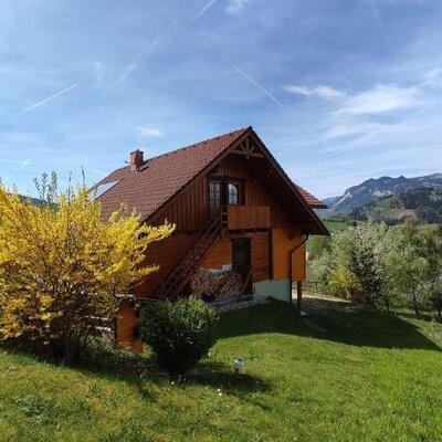 Das Bed and Breakfast von außen, mit Holzbalkon, Außentreppe und Blick auf die Berge.