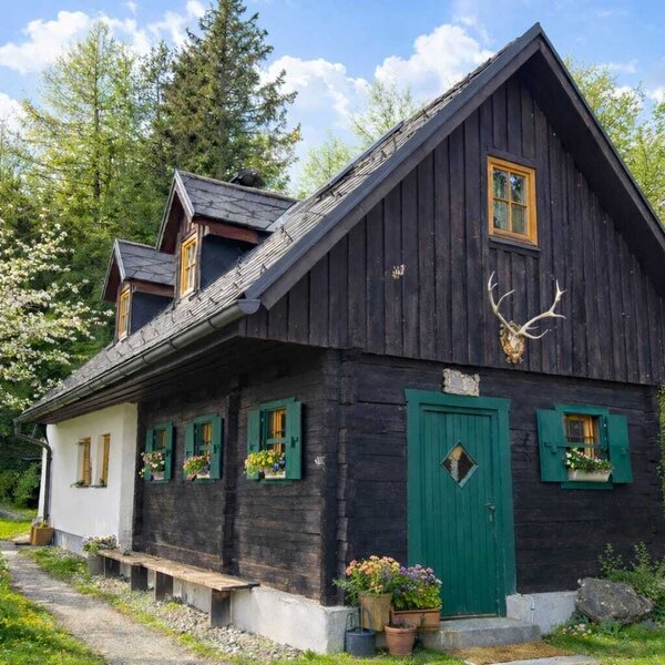 Außenansicht des Bed and Breakfast mit dunkler Holzfassade, weißen Wänden, grünen Fensterläden und einer grünen Eingangstür.