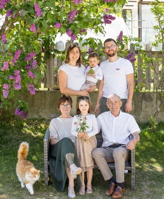 Die Familie des Bauernhofs im Garten mit einem Fliederbusch und einer Katze.