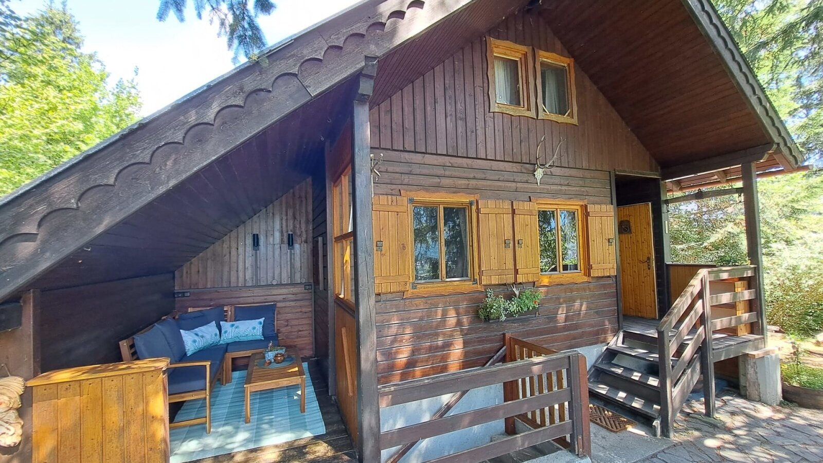 Die charmante Almhütte im rustikalen Holzstil mit einer gemütlichen, überdachten Terrasse.