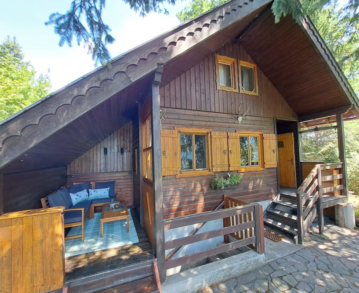Die charmante Almhütte im rustikalen Holzstil mit einer gemütlichen, überdachten Terrasse.