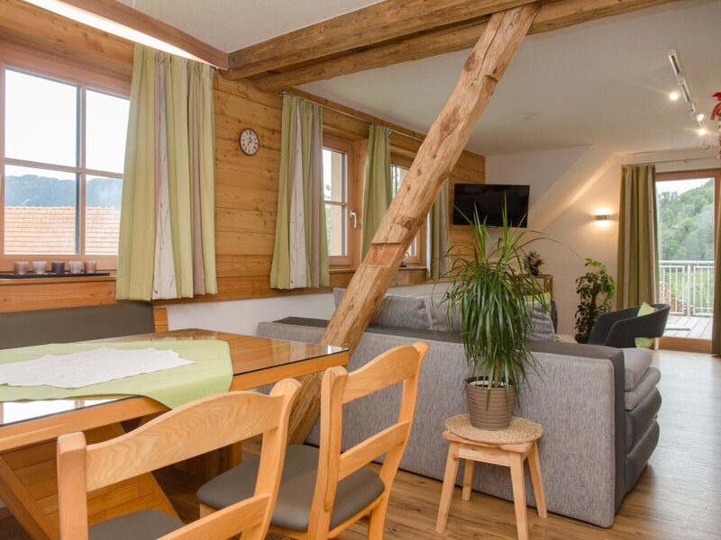 Der Wohn-Essbereich der Ferienwohnung im Bauernhof bietet eine Couch, Sat-TV, einen Esstisch mit Eckbank und direkten Zugang zur Terrasse.
