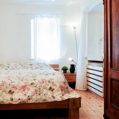 Doppelzimmer im Bauernhof mit Holzbett, floraler Bettwäsche, Nachttisch und einem Holzschrank.
