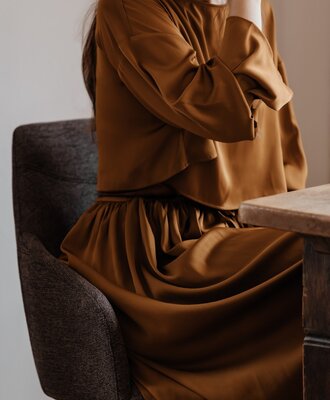 Eine Person sitzt auf einem gepolsterten Stuhl an einem Holztisch.