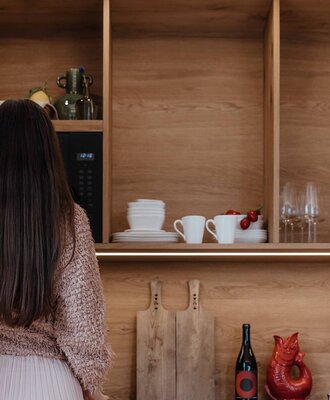 Gut ausgestatteter Küchenbereich mit Holzregalen, Geschirr und Mikrowelle im Bauernhof.