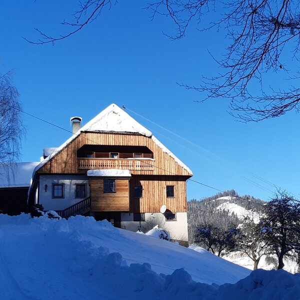 Der Hof mit hölzernem Obergeschoss und Balkon in der verschneiten Winterlandschaft.