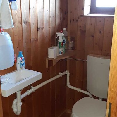 Das WC des Hofes mit Holzwänden, einem Waschbecken und einem Fenster.