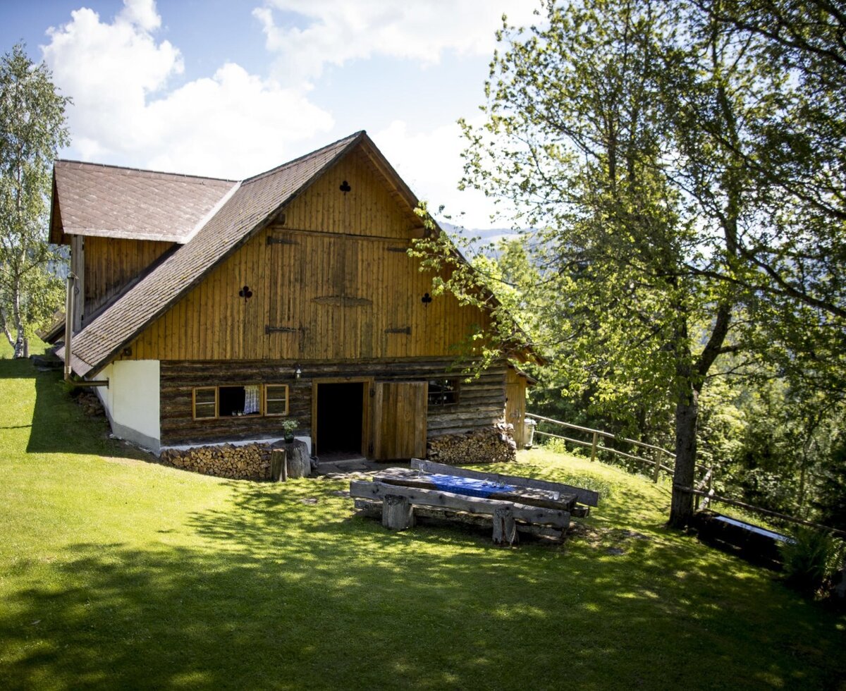 Der Stadl des Hofes mit einem rustikalen Holztisch und Bänken auf der Wiese.