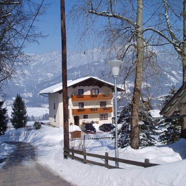 Der Bauernhof im Winter, mit schneebedeckter Umgebung und Bergblick.