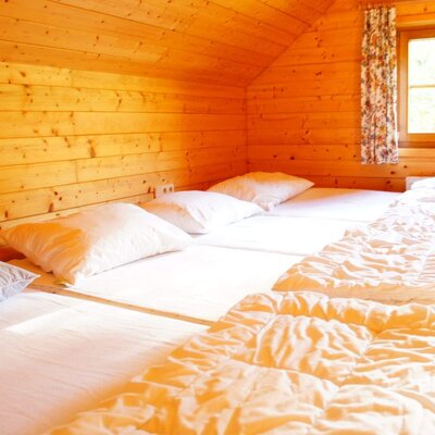 Ein Mehrbettzimmer im Hof mit Holzvertäfelung, drei Einzelbetten und einem Fenster.