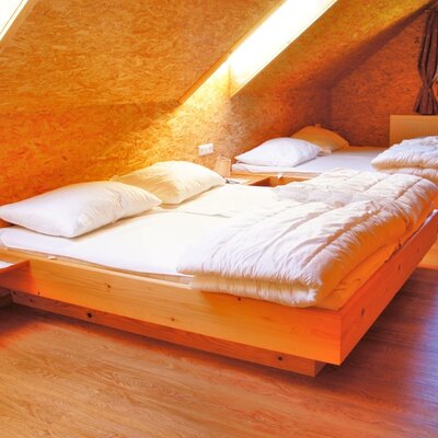 Zweibettzimmer im Hof mit zwei Einzelbetten in Holzrahmen, Holzwänden und Fenster mit Heizung.