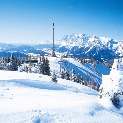 Winterliche Berglandschaft mit präparierten Skipisten und Bergbahnen in der Umgebung des Hofes.