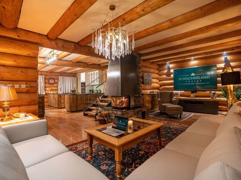 Der gemütliche Wohnbereich des Ferienhauses mit rustikalen Blockholzwänden, einem einladenden Kamin und komfortablen Sofas.