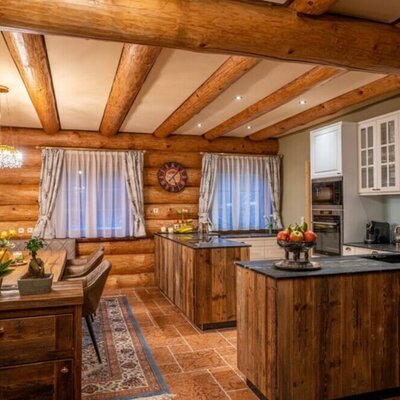Die einladende Küche und der Essbereich des Ferienhauses mit rustikalen Holzwänden, modernen Geräten und warmer Beleuchtung.