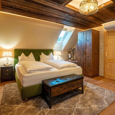Ein gemütliches Schlafzimmer im Ferienhaus mit rustikaler Holzdecke, komfortablem Doppelbett und stimmungsvoller Beleuchtung.