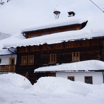 Der Bauernhof von außen, vollständig mit Schnee bedeckt und umgeben von Schneeverwehungen.