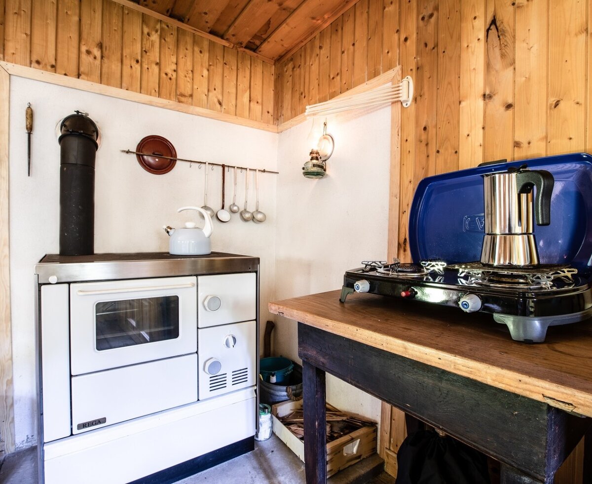 Die Küche im Hof verfügt über einen Holzofen, einen mobilen Gaskocher mit Mokkakanne und einen Wasserkocher.