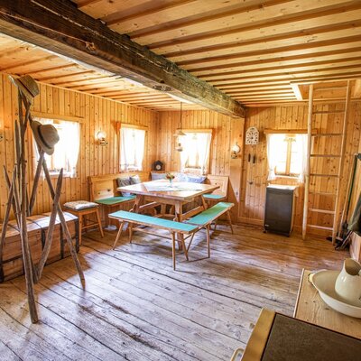 Der Wohn- und Essbereich im Hof ist mit Holzelementen, einer Eckbankgruppe und einer Holzleiter ausgestattet.